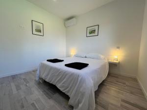 a bedroom with a white bed with two black towels on it at Gîte des Lauriers Roses in Laurac-en-Vivarais +20 photos