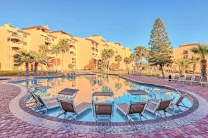 a pool with chairs and tables in front of a building at Gorgeous Third-Level Condo Princesa D-308 in Puerto Peñasco