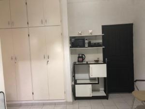 a kitchen with white cabinets and a small refrigerator at Chambre indépendante in Port-Gentil