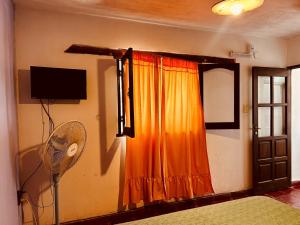 a room with an orange curtain and a fan at Las Pircas Apartamentos - Centro de Cafayate in Cafayate