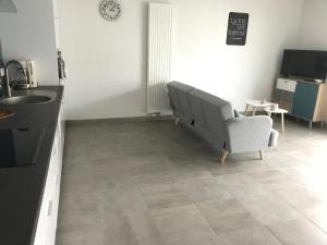 a kitchen with a couch and a chair and a sink at Appartement récent et à la déco moderne in Damgan