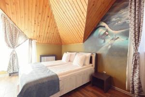 a bedroom with a bed with a painting on the wall at Pensiunea Dezire in Baile Unu Mai