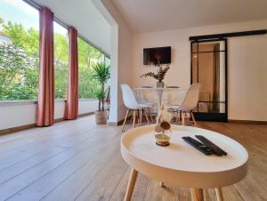 a living room with a table and white chairs at Écrin de Verdure - Design & Confort T2 38m2, WIFI, Piscine & Plage à 200m in La Grande Motte