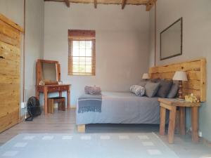 a bedroom with a bed and a table and a mirror at The Cottage in De Rust +49 photos