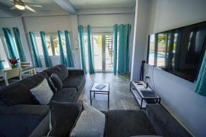 a living room with a couch and a flat screen tv at Villa Armoniosa Ocean View 2BR w/ Beachfront Pool - Upper Level in Placencia