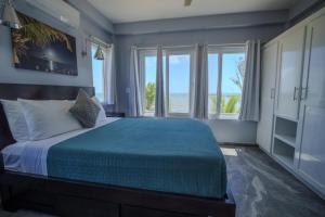 a bedroom with a large bed with a large window at Villa Armoniosa Ocean View 2BR w/ Beachfront Pool - Upper Level in Placencia +28 photos