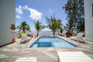 a swimming pool with chairs and a view of the ocean at Villa Armoniosa Ocean View 2BR w/ Beachfront Pool - Upper Level in Placencia