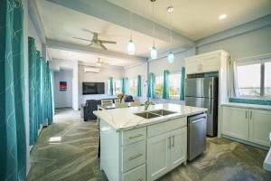 a kitchen with a sink and a living room at Villa Armoniosa Spacious Beachfront 2BR with Pool - Lower Level in Placencia