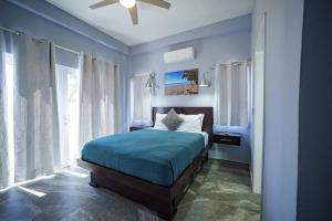 a blue bedroom with a bed and a ceiling fan at Villa Armoniosa Spacious Beachfront 2BR with Pool - Lower Level in Placencia +23 photos