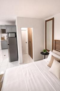 a white bedroom with a large bed and a kitchen at The Oxford Suite in Kingston