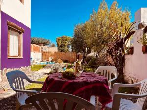 a table with a purple tablecloth and white chairs at Las Pircas Apartamentos - Centro de Cafayate in Cafayate
