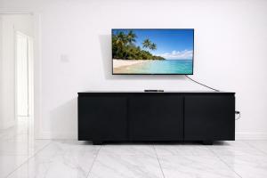 a tv on a wall in a room with a beach at Redhills Escape in Kingston