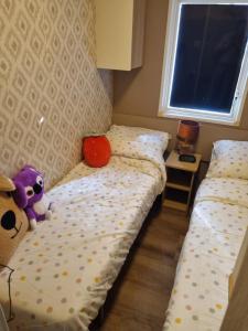 a small bedroom with two beds and a stuffed animal at Stacaravan 161 Capfun camping Bongerd 5 sterren Gezin 5 personen in Tuitjenhorn +19 photos