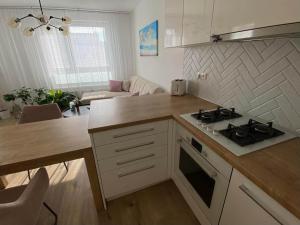 a kitchen with a stove top oven next to a living room at Bratislava, LUCAO Family Apartment, Balcony, Free Parking, Aircondition, 8km Old Town in Bratislava