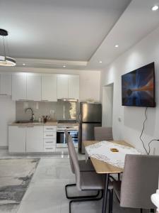 a kitchen with white cabinets and a table with chairs at Peaceful House in Përmet