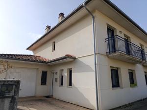 a white building with a balcony on the side at Casa María House in Zubiri