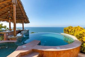 a swimming pool in a resort with the ocean in the background at Luxe 3 King BR Villa | Infinity Pool + 220° Views in Puerto Vallarta