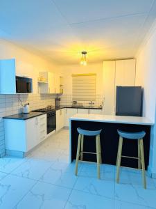 a kitchen with a counter and two stools at Brytelight Luxe 1 Bedroom in Rustenburg +5 photos