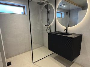 a bathroom with a shower with a round mirror at Pool & Sauna Retreat - Private Studio Apartment Porsgrunn in Porsgrunn