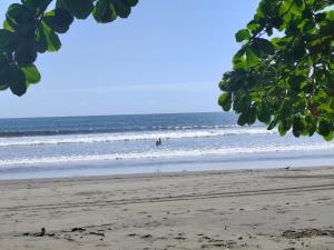 a beach with a person standing in the ocean at Casa de playa MC in Quepos