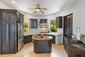 a kitchen with black cabinets and a ceiling fan at Luxe 3 King BR Villa | Infinity Pool + 220° Views in Puerto Vallarta