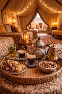 a room with a table with a tea kettle and plates of food at Achabou Desert Camp in Merzouga