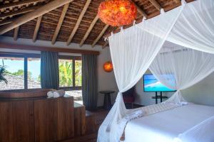 a bedroom with a bed with white drapes and a television at Amaia Trancoso Hotel in Trancoso
