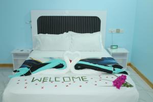 a bed with a welcome sign and flowers on it at Ocean Echo Villa in Mathiveri
