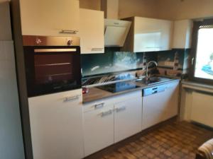eine Küche mit weißen Schränken und einem Herd mit Backofen in der Unterkunft Ferienwohnung Freiling in Wilhelmshütte
