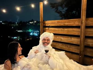 a man and a woman sitting in bed with a glass of wine at La Casa de Blue in Guarne +3 photos