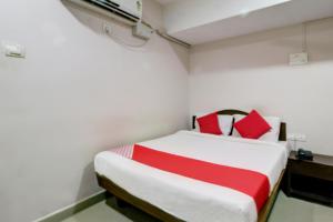 a bedroom with a bed with red and white pillows at Hotel O Ksp Lodge in Neyveli