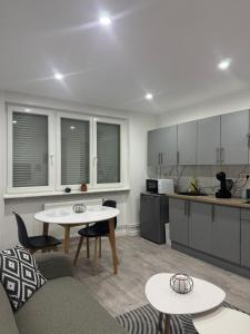 a kitchen and a living room with tables and chairs at Appart' Cosy proche Mulhouse in Illzach