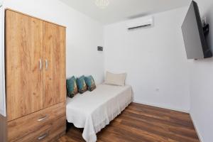 a bedroom with a white bed and a wooden cabinet at Elysian by the sea in Nisaki