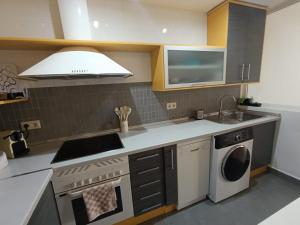 a kitchen with a stove and a sink and a microwave at La Alameda Jardines del Prado -Amplio y con ascensor- in Talavera de la Reina