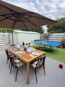 a wooden table with chairs and an umbrella at Les Moussaillons, plage à pieds in Jullouville-les-Pins