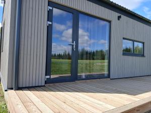 a large glass door on a building with a wooden deck at Elenos sodyba in Puorai