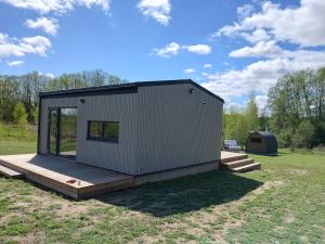 a tiny house with a deck and a tent at Elenos sodyba in Puorai