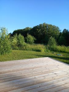 a wooden deck with a field and trees in the background at Elenos sodyba in Puorai