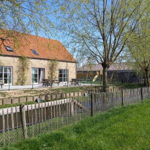 a fence in front of a building with a tree at 't Ooievaarsnest in Veurne