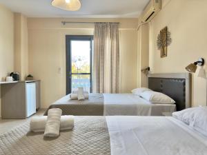 a hotel room with two beds and a window at INO Luxury Rooms in Paralia Katerinis