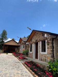 a stone house with flowers in front of it at Condominio Entre Bosques Cabaña 9 in Piedecuesta