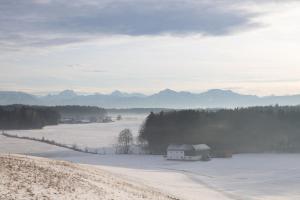a snow covered field with a house in the distance at Individual room surrounded by nature in Sankt Georgen bei Salzburg