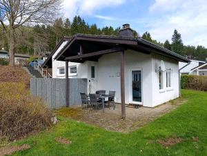 a small white house with a table and chairs at Maja am See in Biersdorf am See