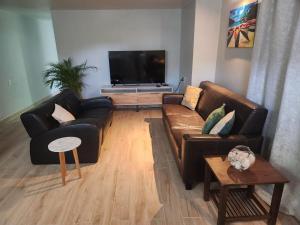 a living room with leather couches and a flat screen tv at Kelly's Vacation Nest to Relax and Reactivate in Willemstad