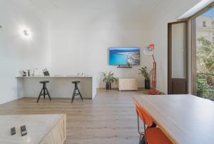 a living room with a table and a tv on the wall at Palazzo Lucatelli Suite - Centro in Trapani