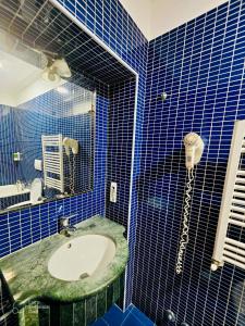 a blue tiled bathroom with a sink and a phone at Beauty Rooms in Rome