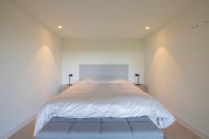 a bedroom with a large bed with white sheets at Guesthouse 'Elements' with panoramic views in Bergen