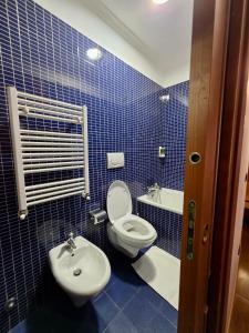 a blue tiled bathroom with a toilet and a sink at Beauty Rooms in Rome