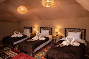 a bedroom with two beds with swans on them at Sahara wellness camp in Merzouga +117 photos
