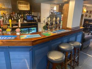 a blue bar with stools at a bar with a counter at The Phelips Arms in Montacute +20 photos